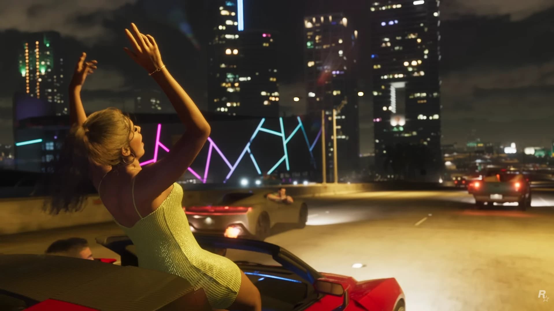 Una chica de pie en un descapotable celebra con los brazos en alto en una autopista de Vice City de noche, con los rascacielos iluminados al fondo.