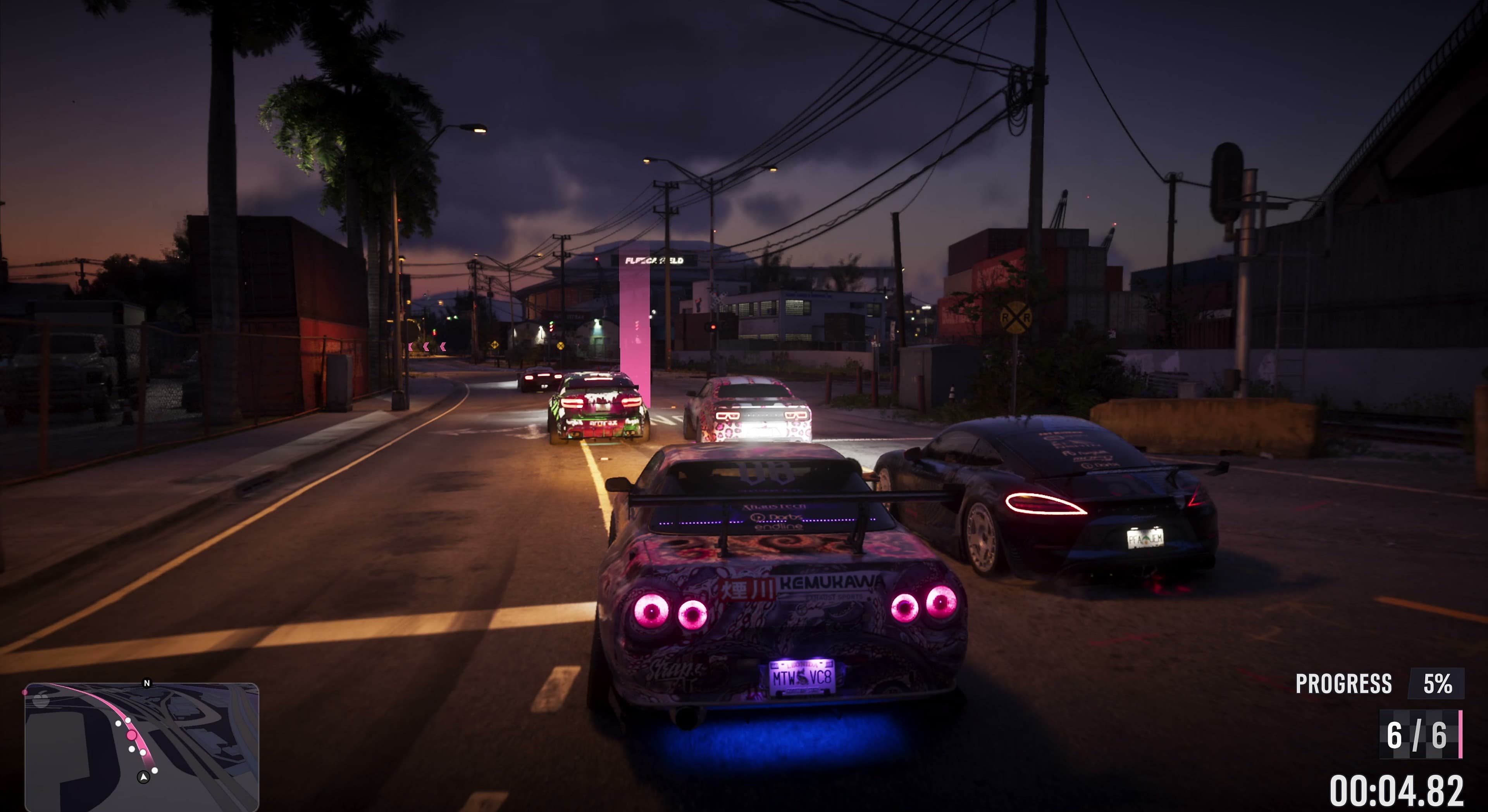 Race cars at night between warehouses, with the Fleeca Field name lit up in the background