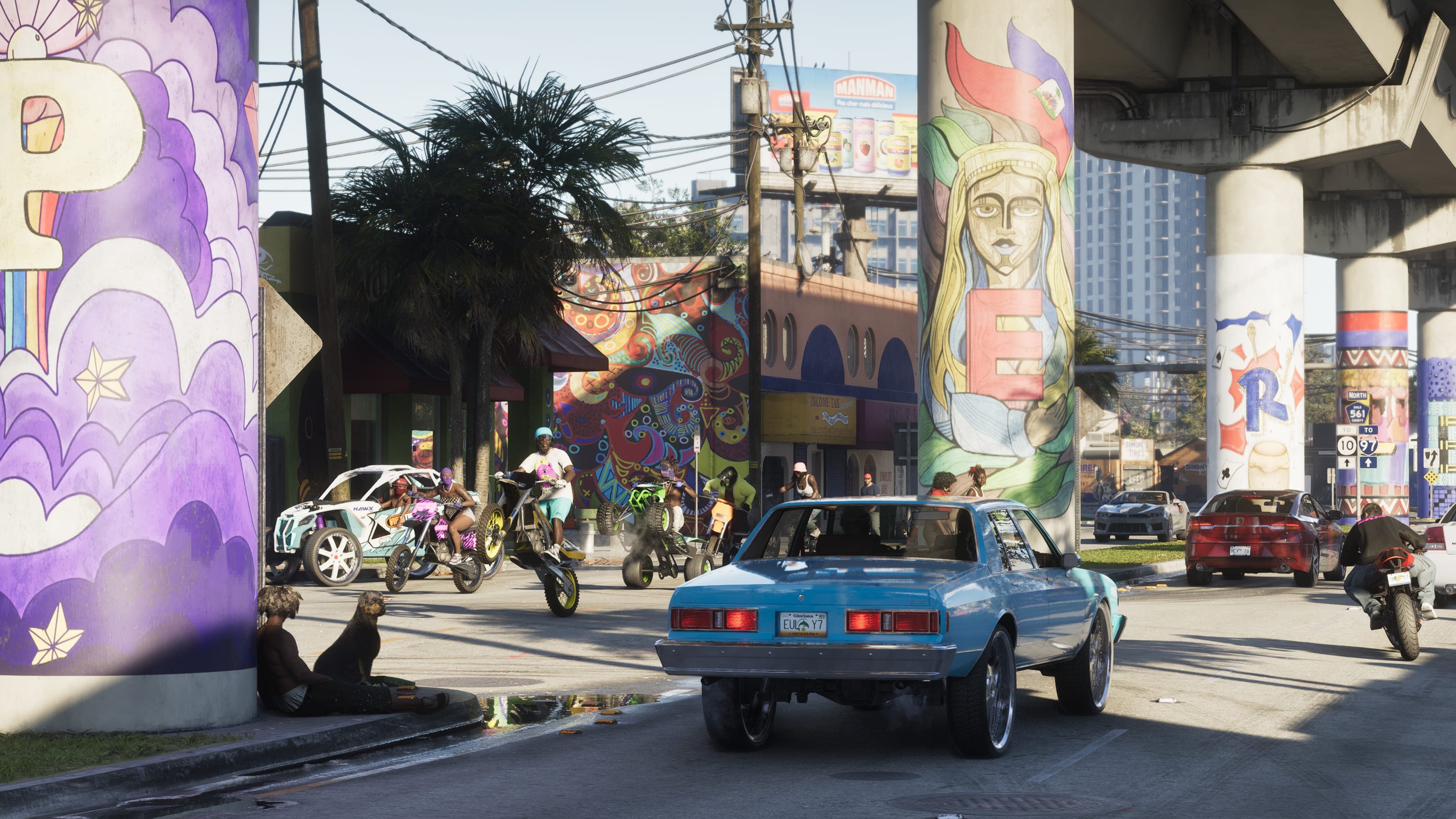 A Vice City street under an overpass with mural-covered pillars, motorbikes pulling wheelies, a classic blue car and a billboard in the background.