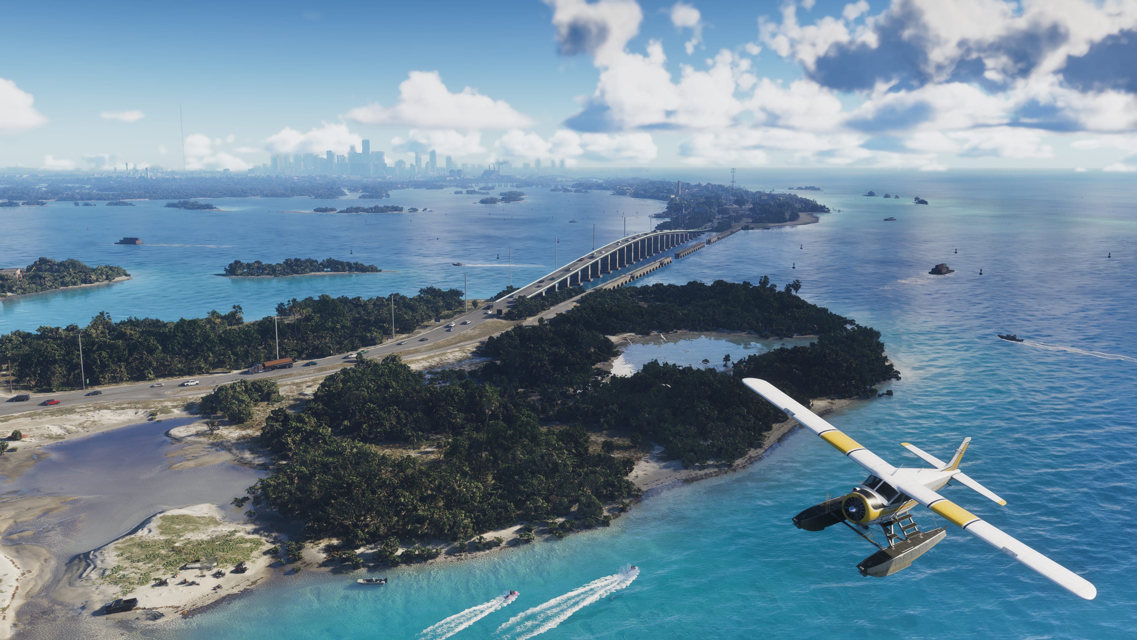 Aerial view of green keys surrounded by turquoise sea, with a long bridge stretching to the horizon, a seaplane in flight and boats leaving wakes.